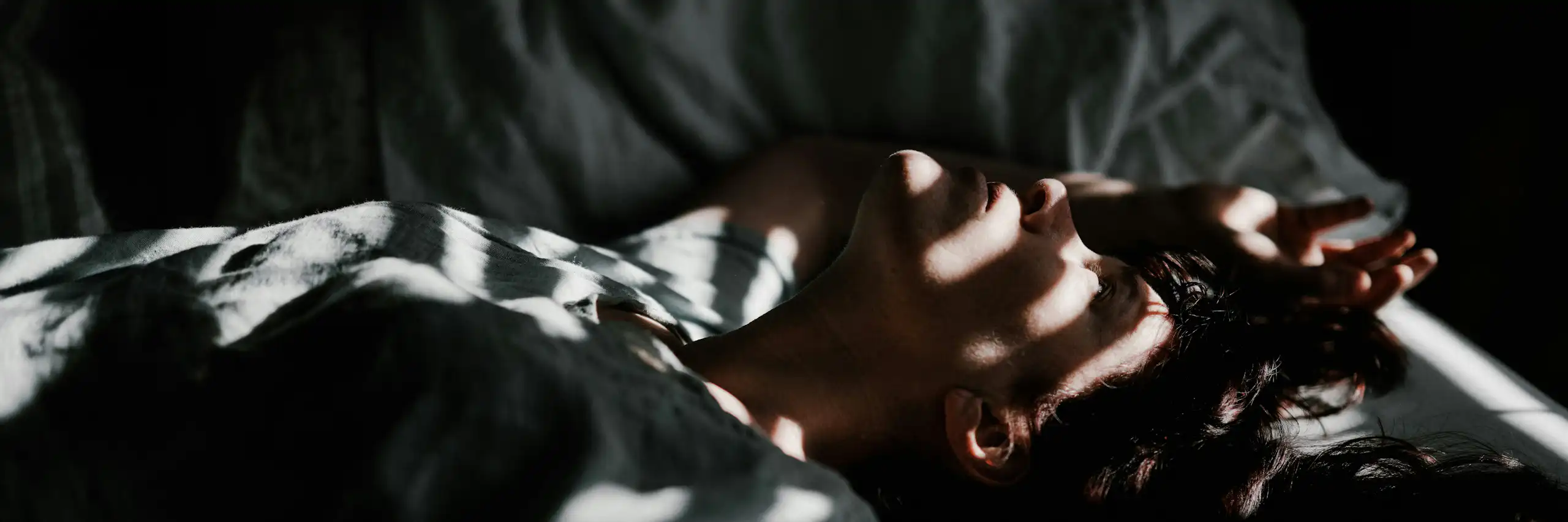 Un homme est couché dans un lit dans la pénombre.