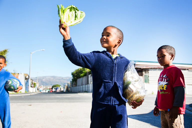 A child stands smiling holding lettuce and bean sprouts