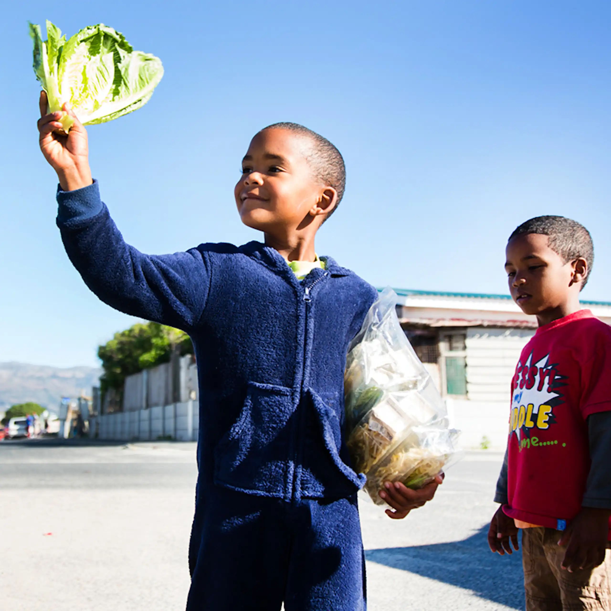A child stands smiling holding lettuce and bean sprouts