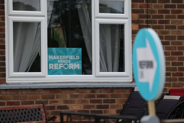 window of a house showing a poster reading 'makerfield needs reform'