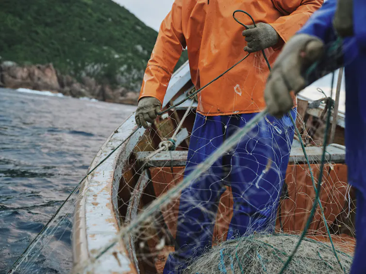 Deux personnes dans un canot agrippent un grand filet de pêche