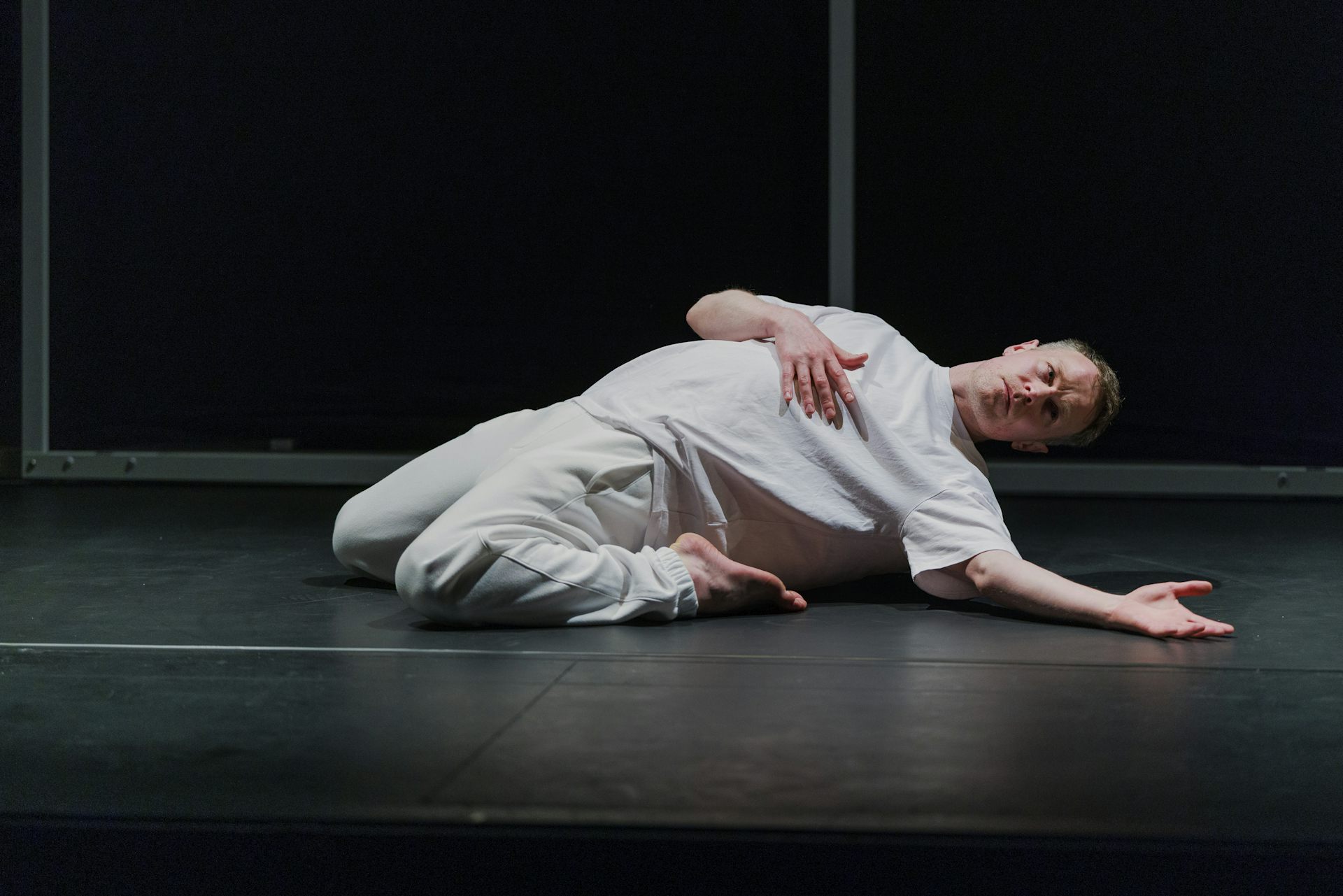 A dancer dressed in white is pictured on the ground mid-dance.