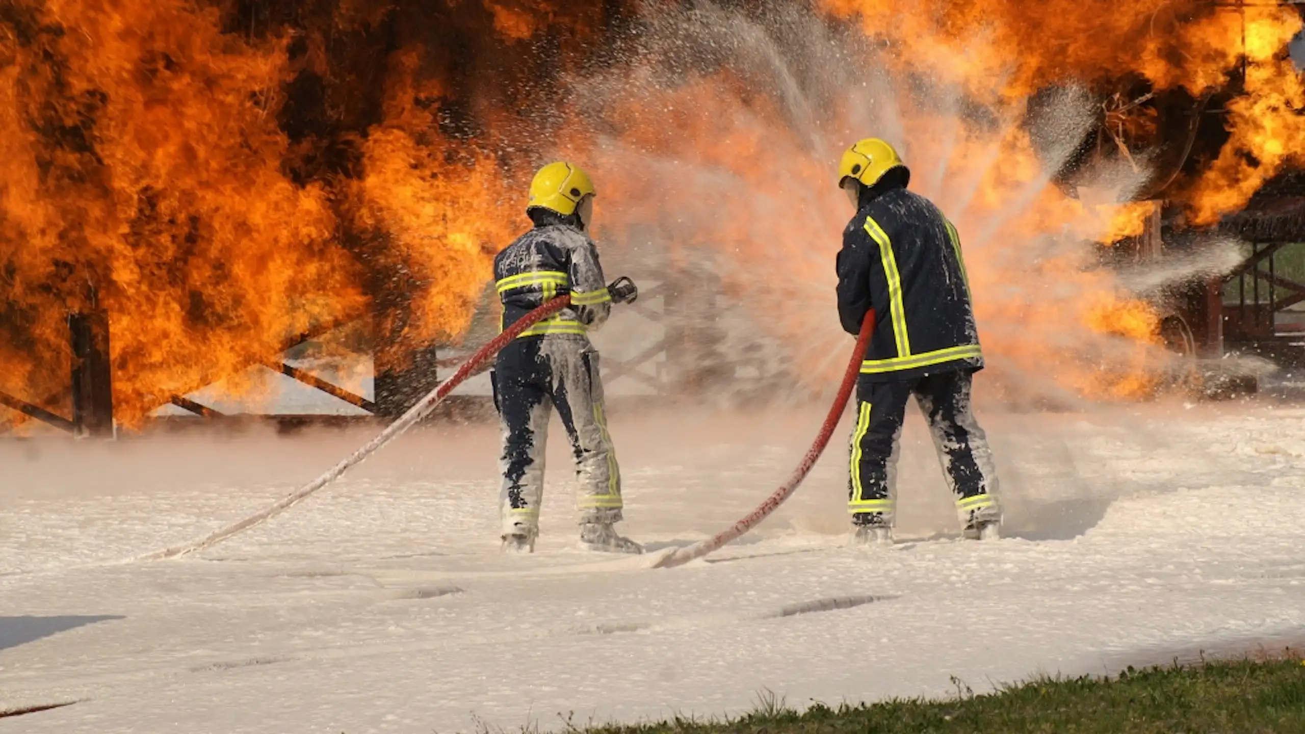 firefighters spraying foam on fire.