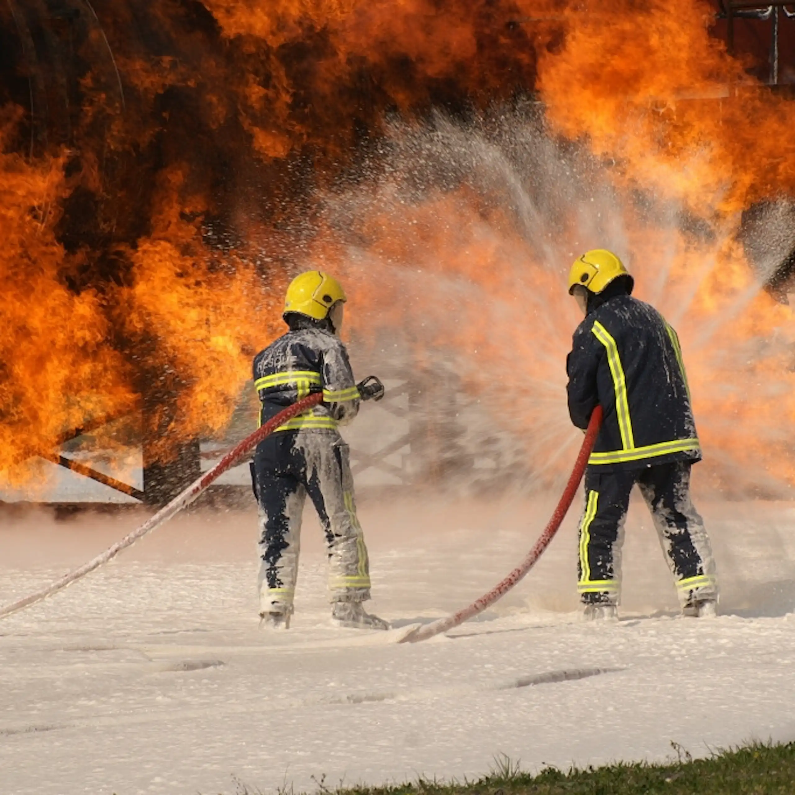firefighters spraying foam on fire.
