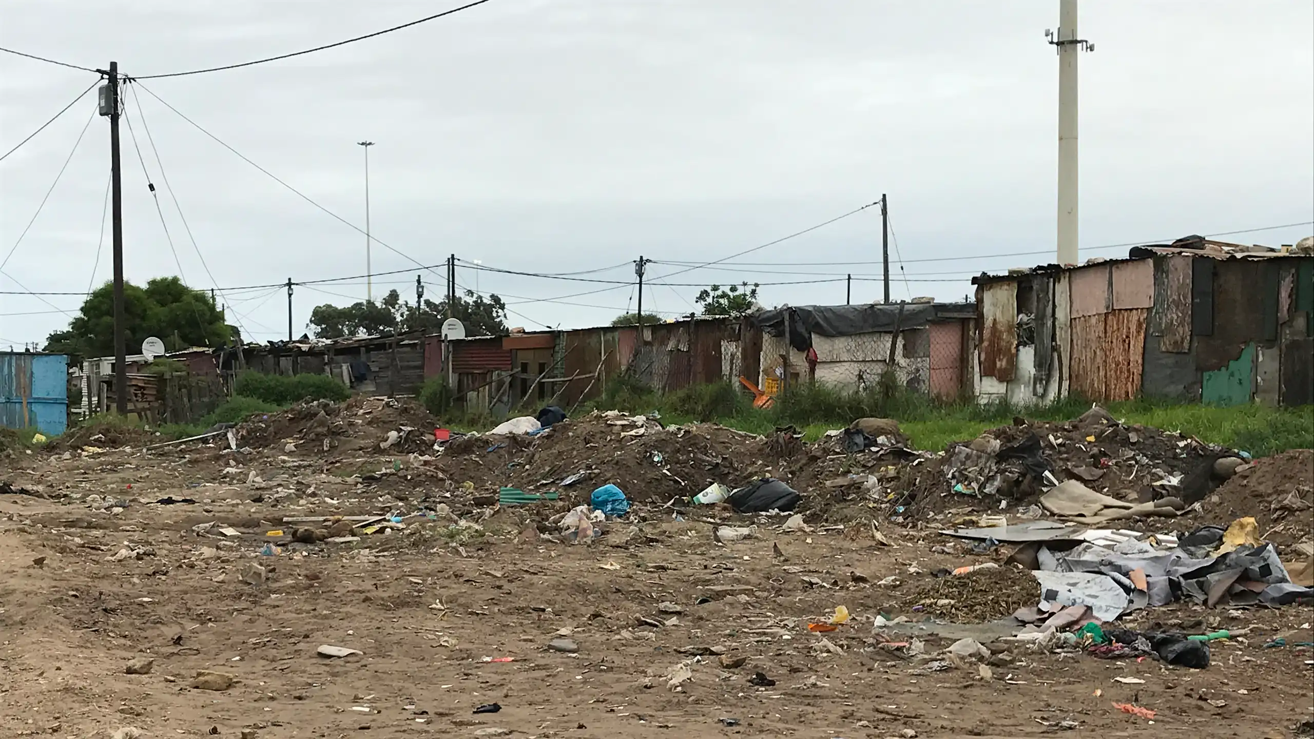 Shacks in the background of an area of open land