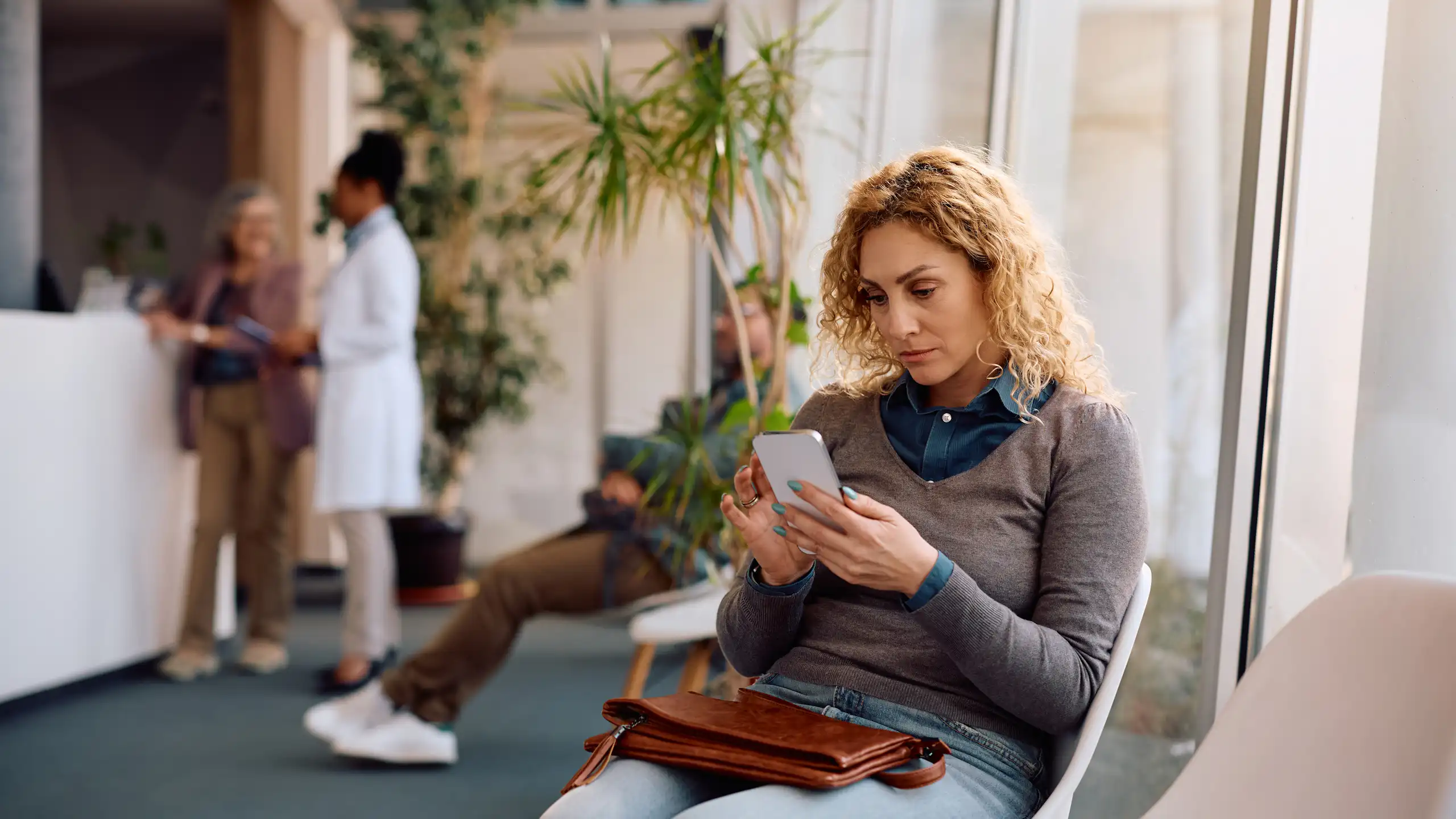 Une femme sur son smartphone, en train d'attendre un rendez-vous médical.