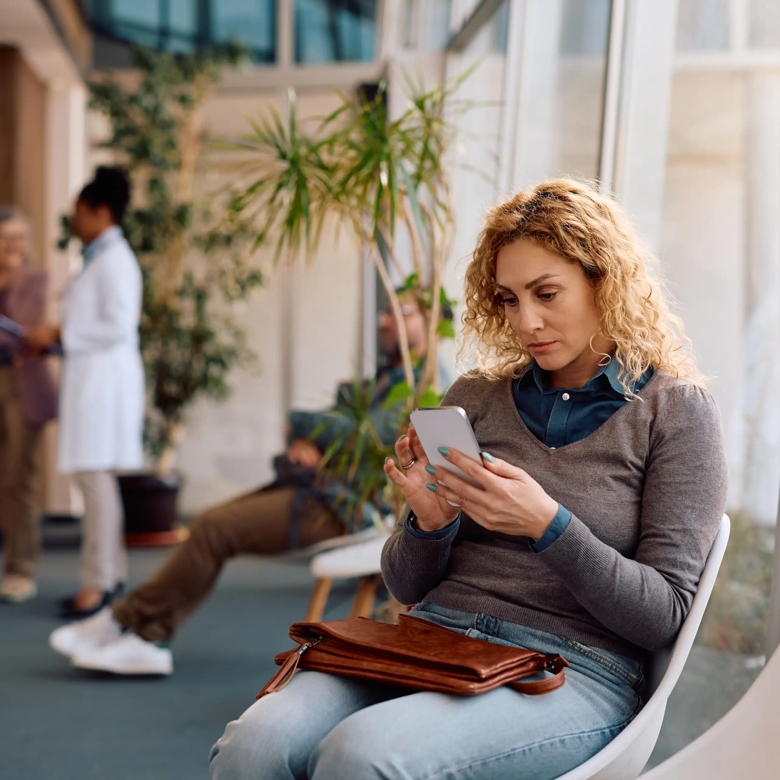 Une femme sur son smartphone, en train d'attendre un rendez-vous médical.