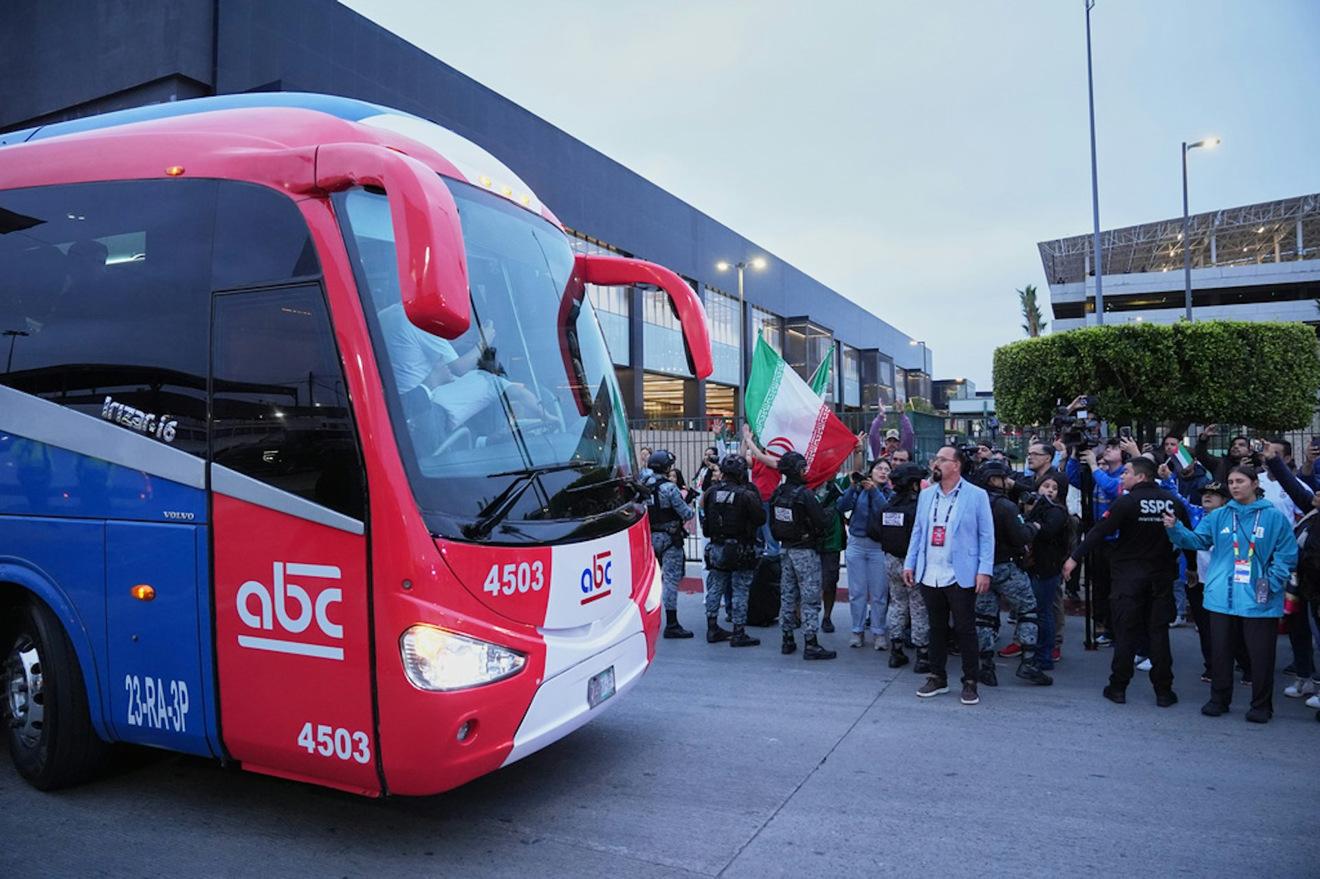 A bus passes by a crowd of people.