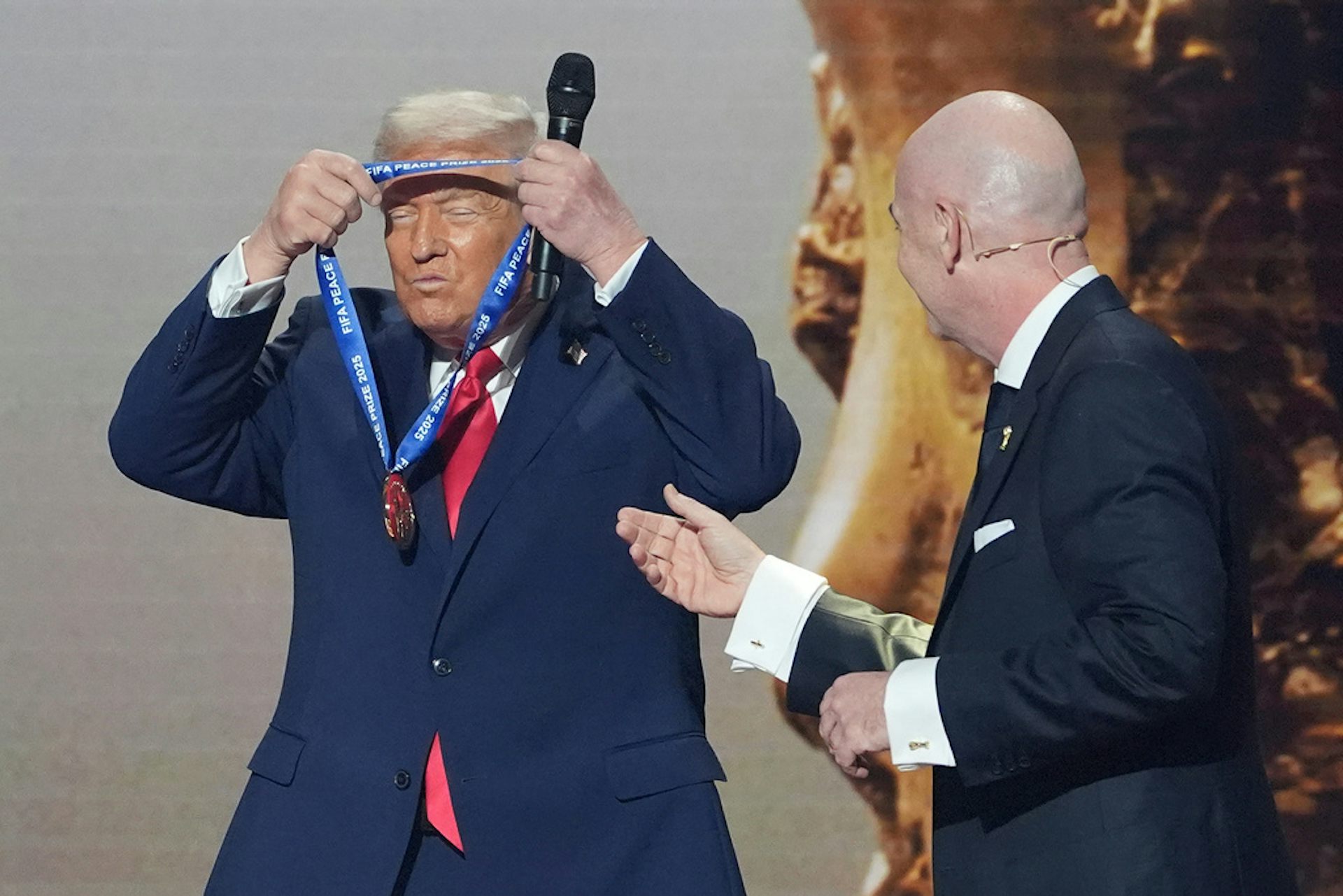A man in a suit puts a medal around his neck.