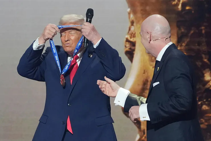 A man in a suit puts a medal around his neck.
