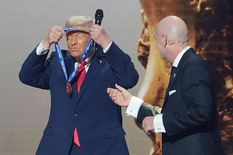 A man in a suit puts a medal around his neck.
