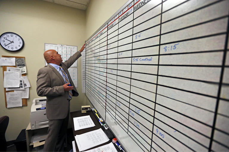 A man reviewing a printed interpreting schedule posted in an office