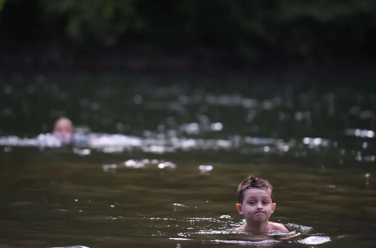 A young boy swims in a river.