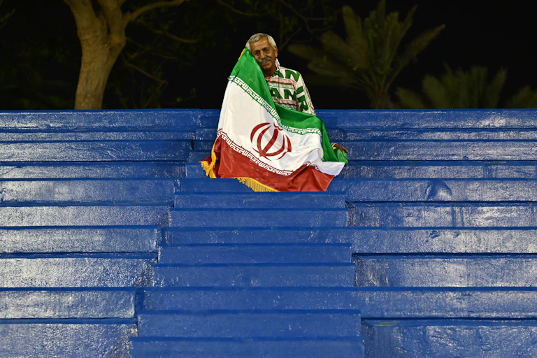 A man sits on seating draped in a flag.