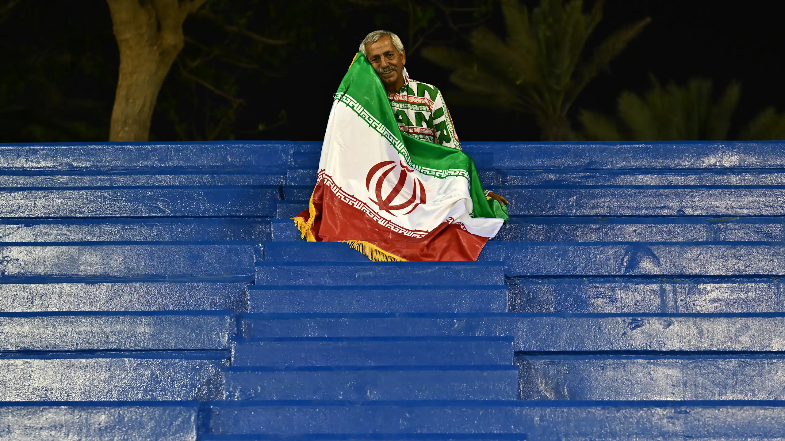 A man sits on seating draped in a flag.