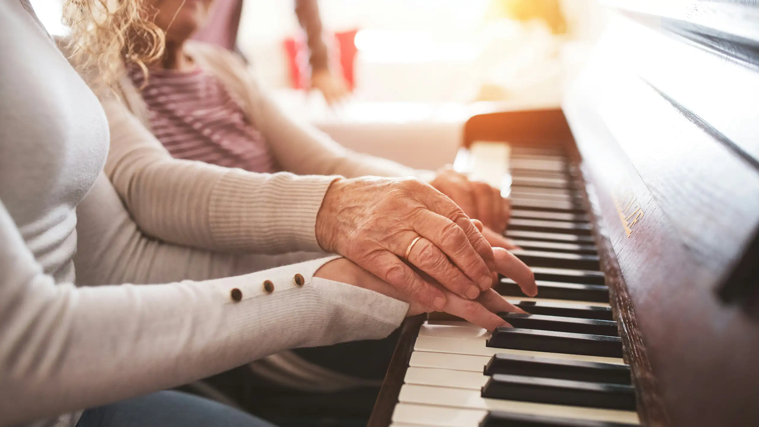 Photo of two sets of hands — one younger and one older — on a piano keyboard