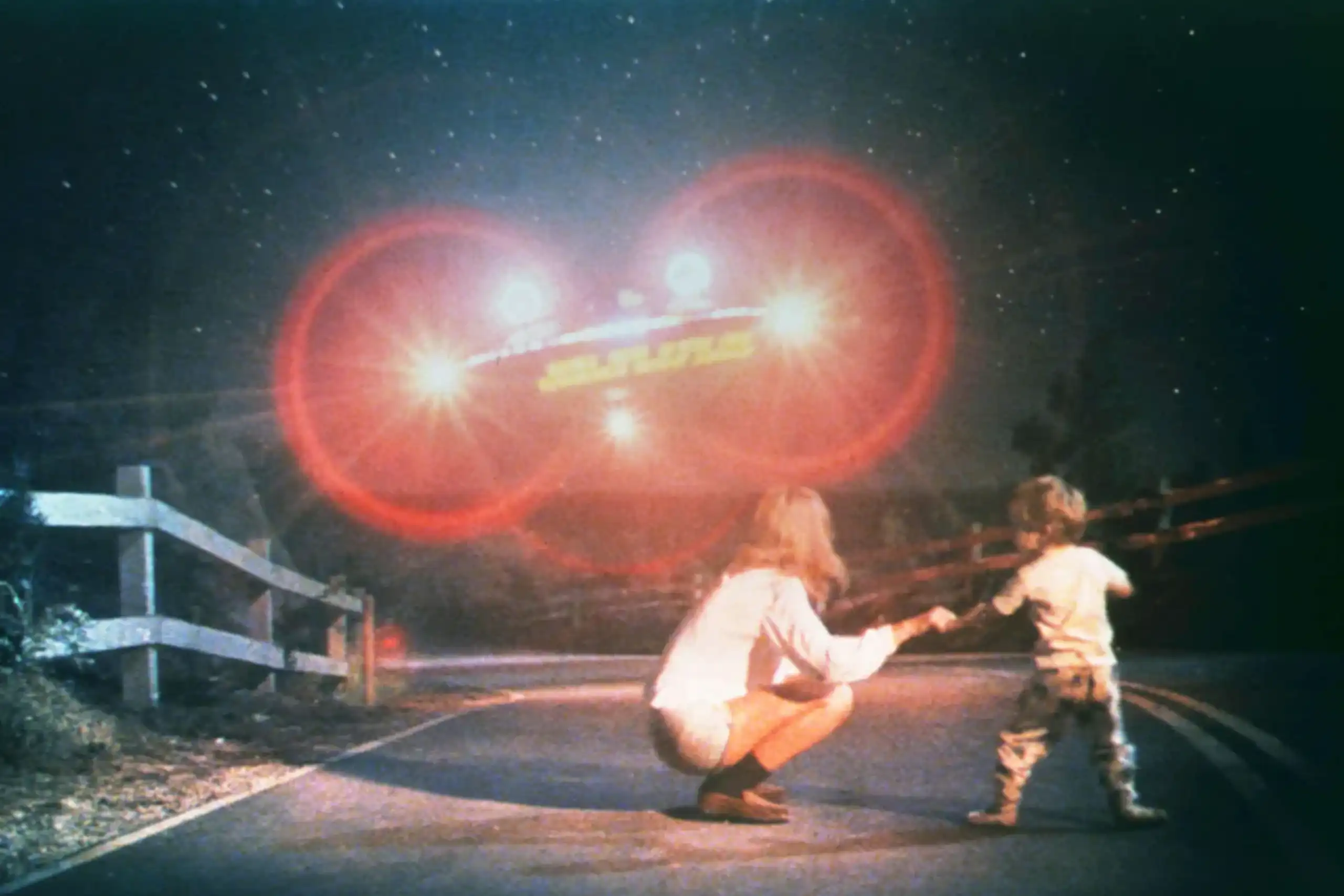 Capture d'écran : l'enfant et sa mère, en pleine nuit, face à une machine volante avançant plein phare dans leur direction.