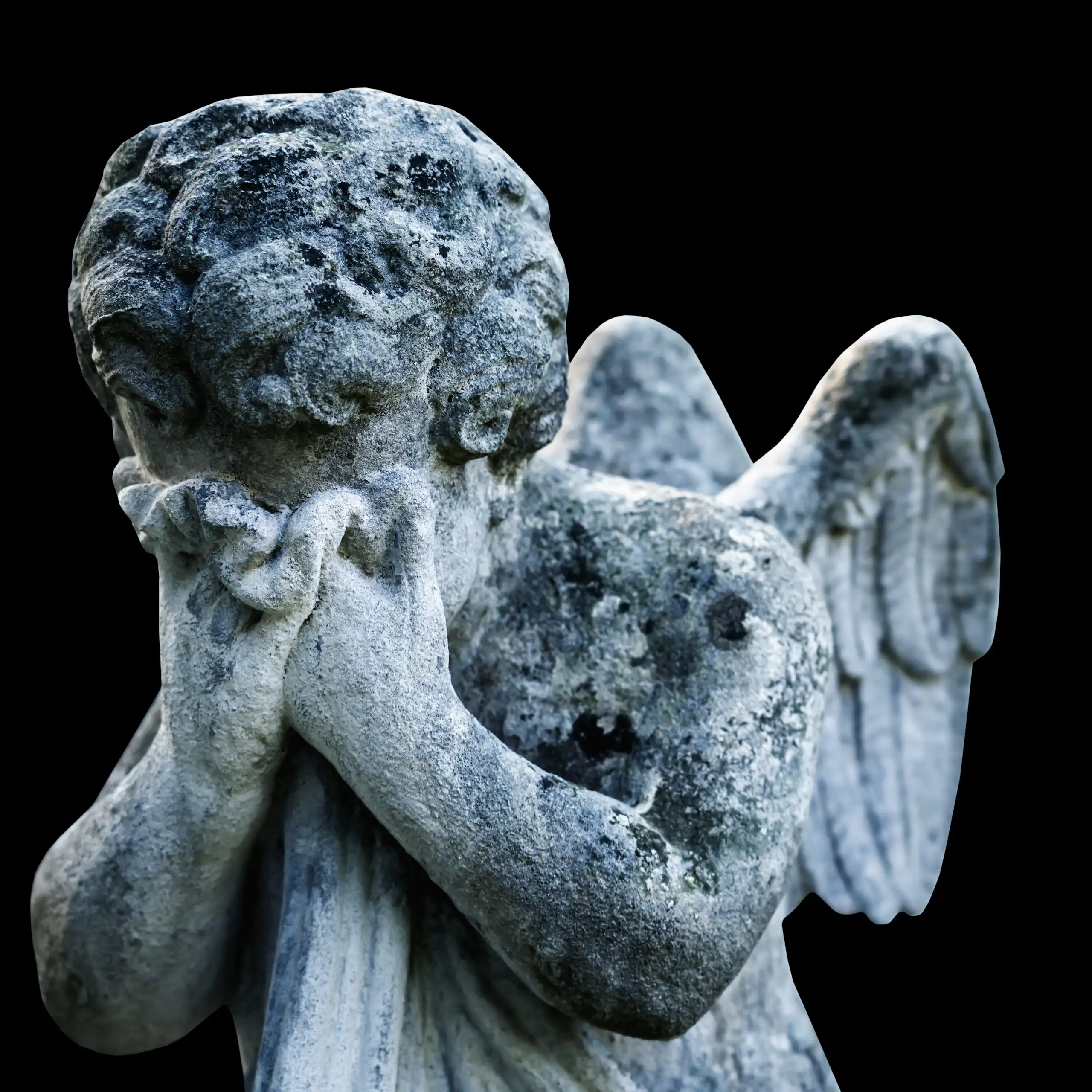Sad angel as a symbol of pain and death. Ancient statue isolated on a black background