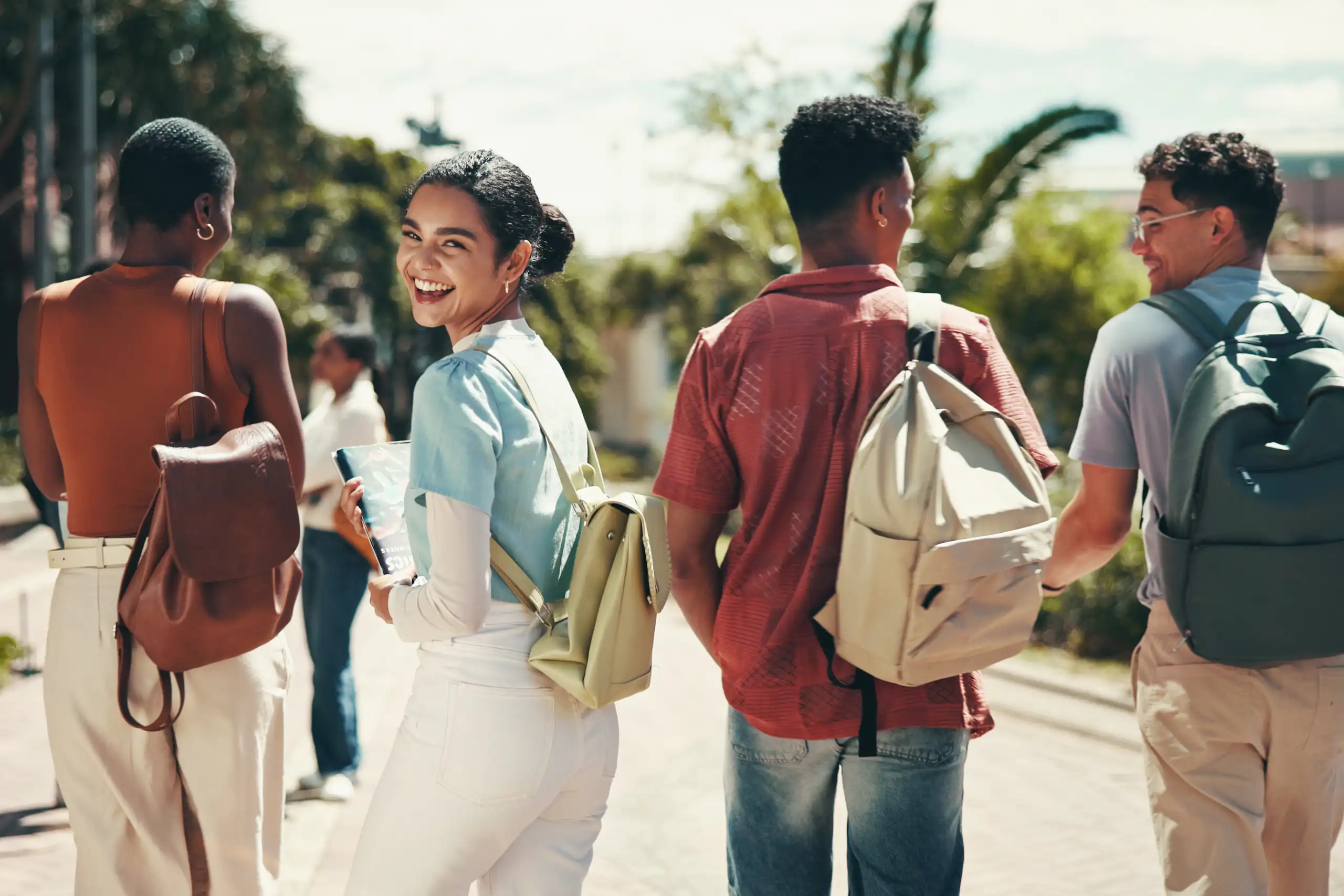 Group of young people walking; girl looks back smiling