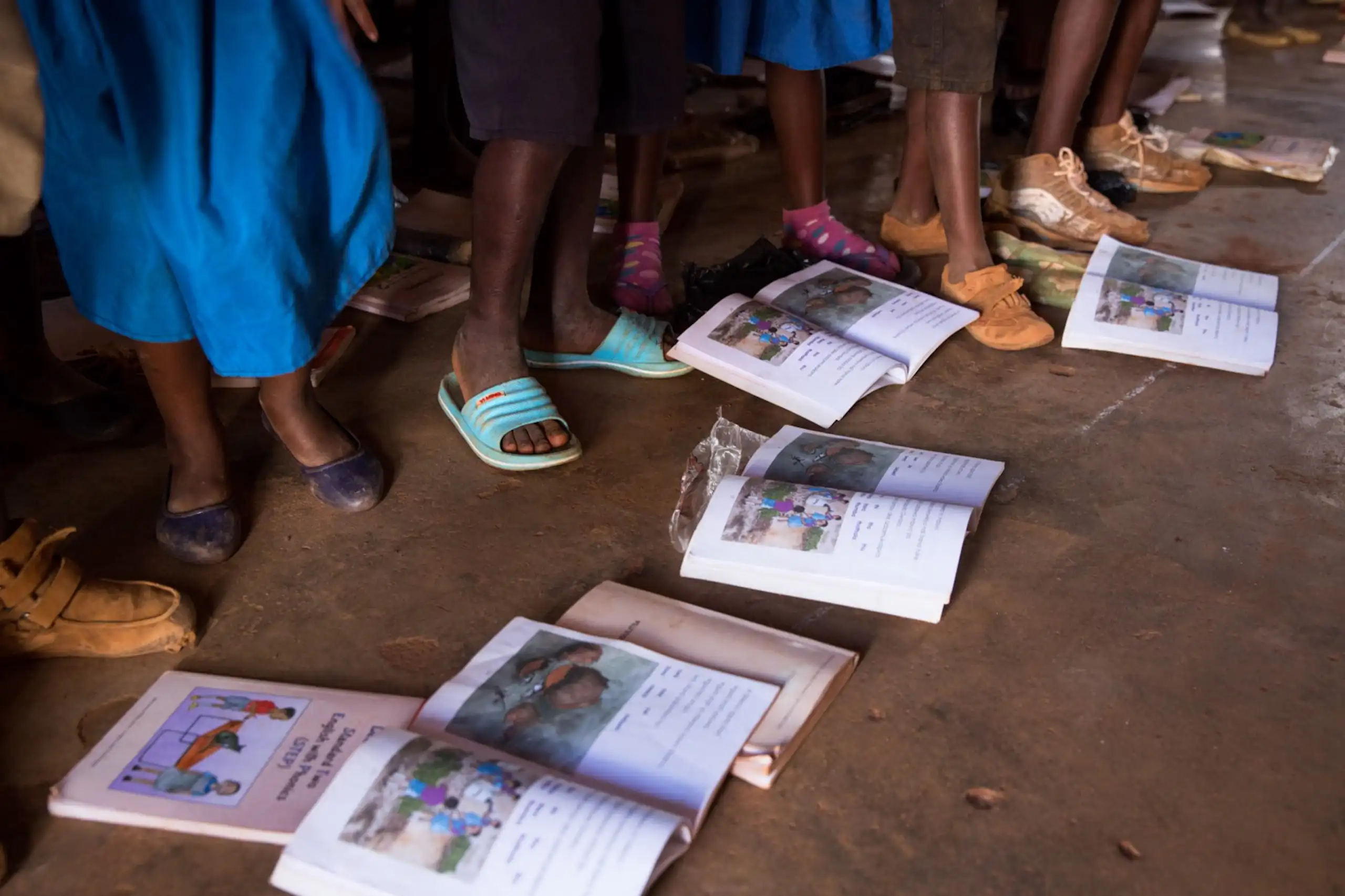 Open books on the ground; children's feet and legs