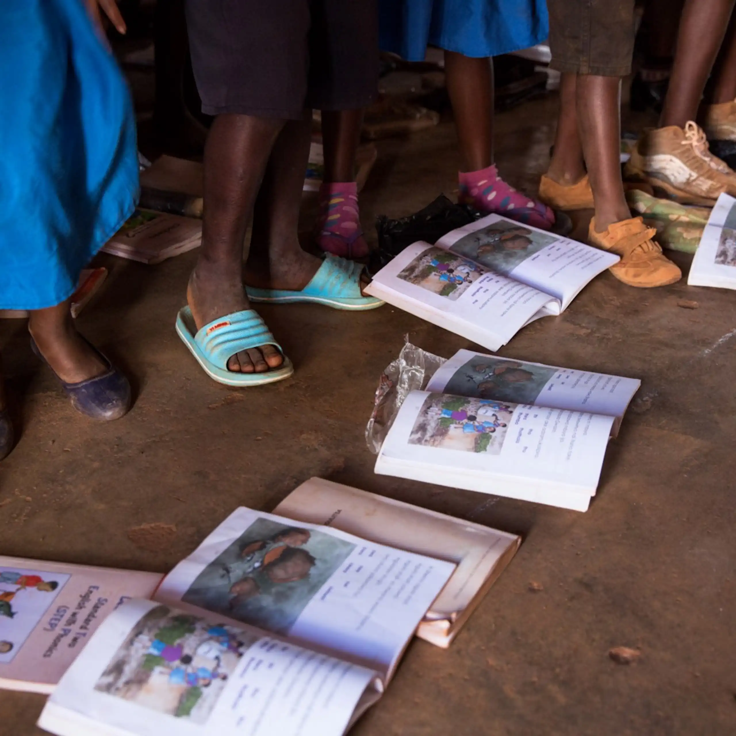 Open books on the ground; children's feet and legs