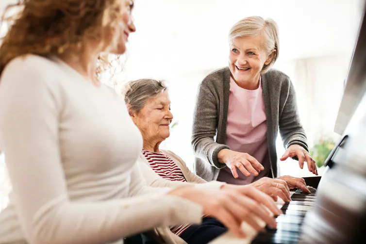 Three women of different ages around a piano