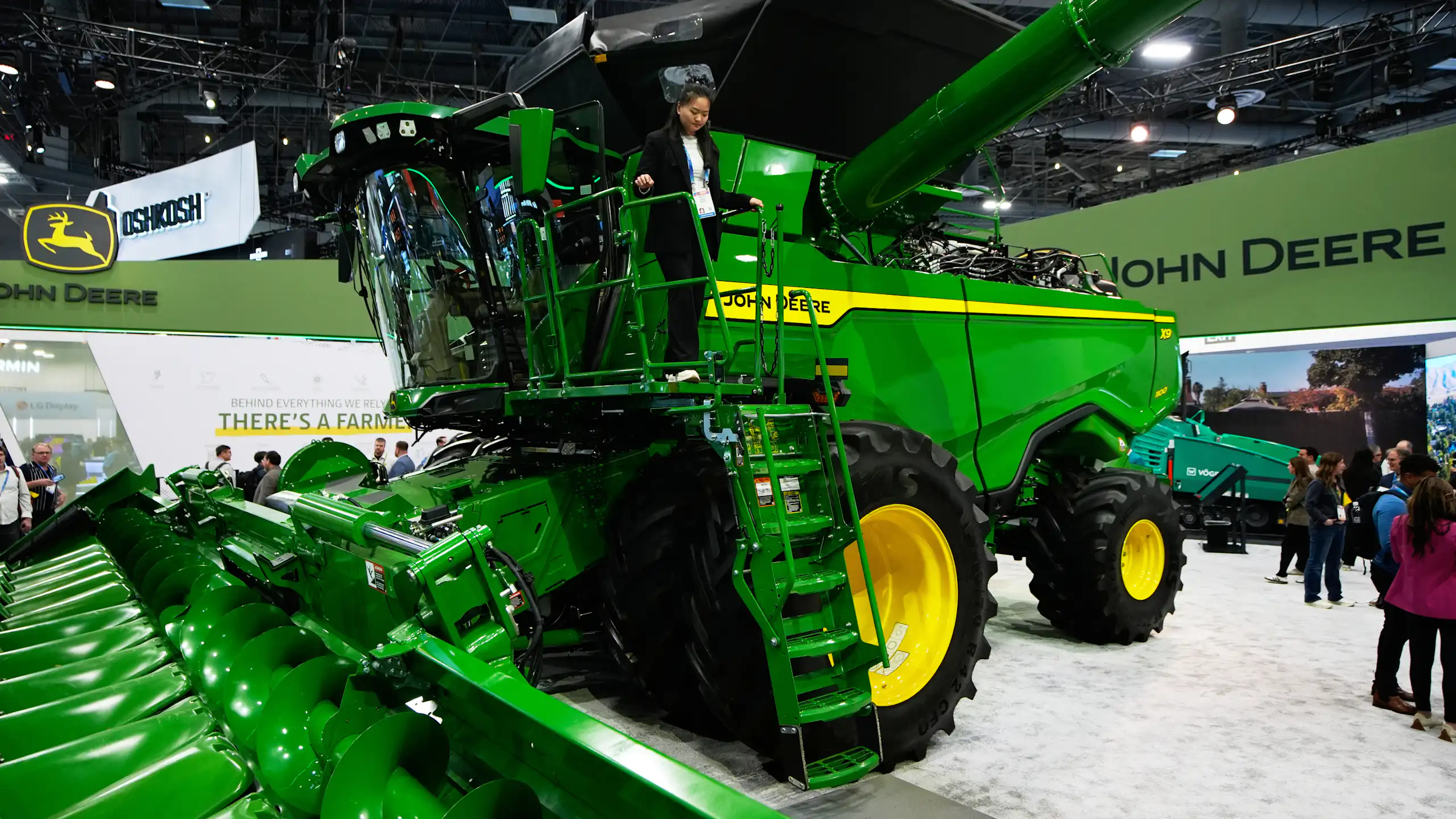 A customer walks on a massive green combine at the John Deere booth during the 2026 CES tech show in Las Vegas, Nevada.