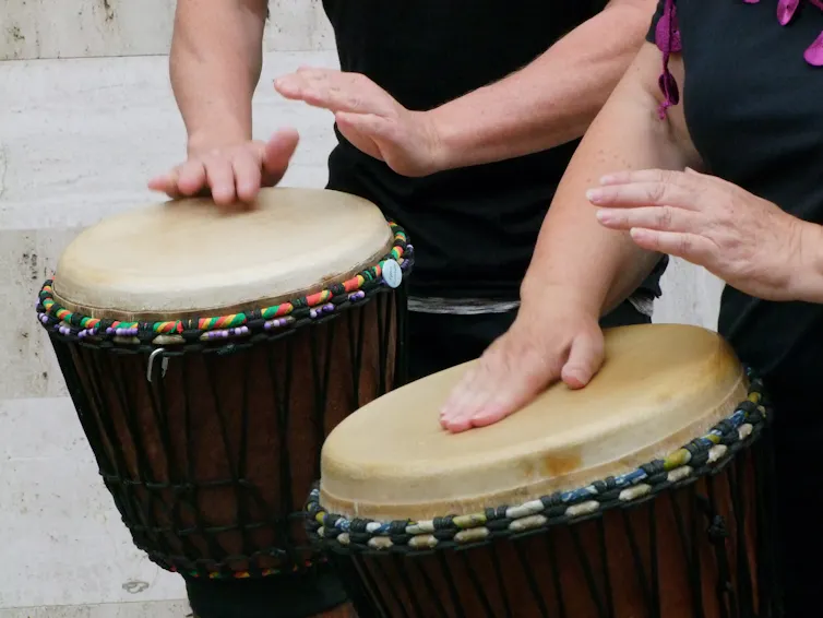 Close-up photo of two people's hands playing drums
