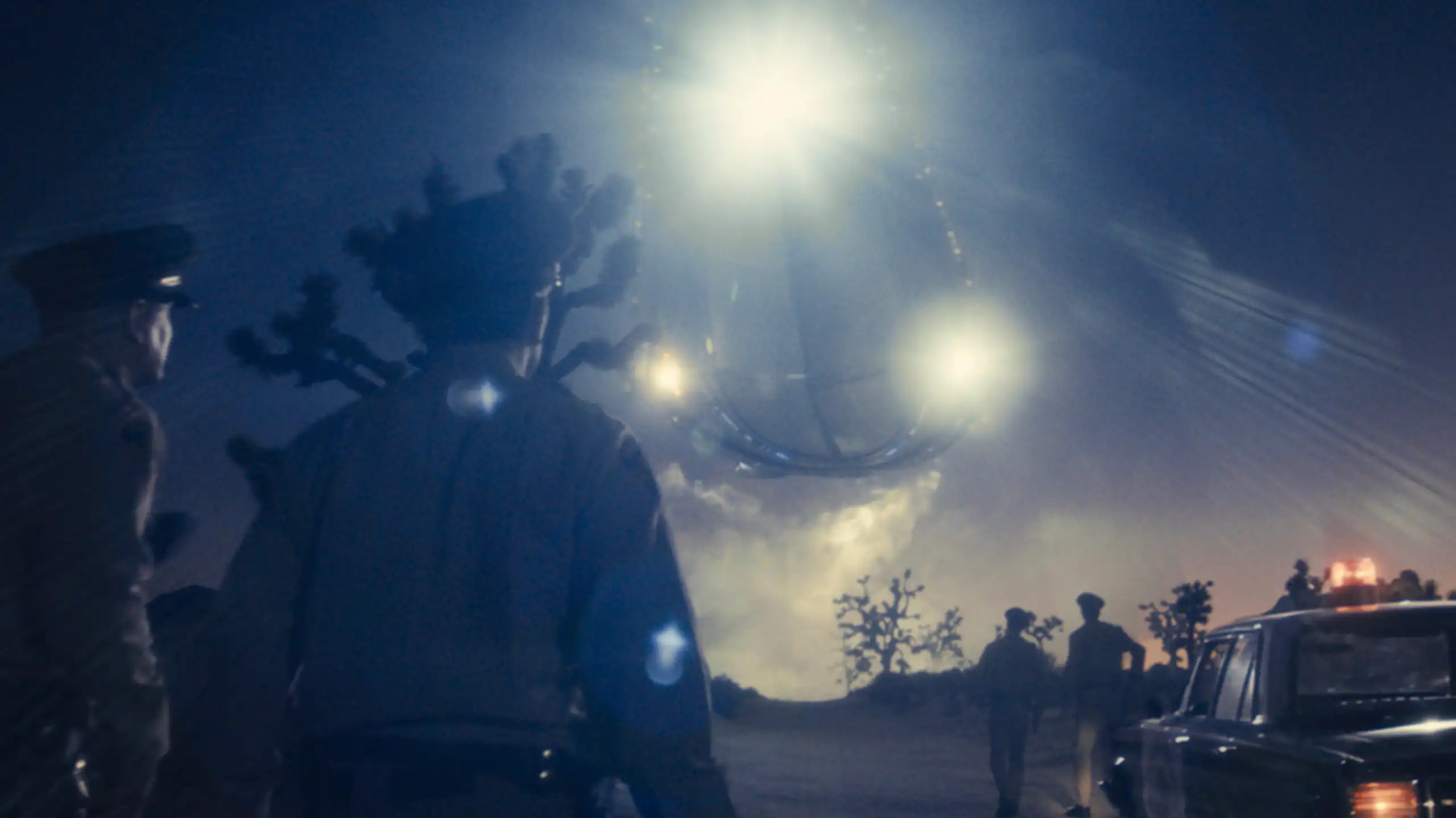 People standing in a field as a spaceship approaches.