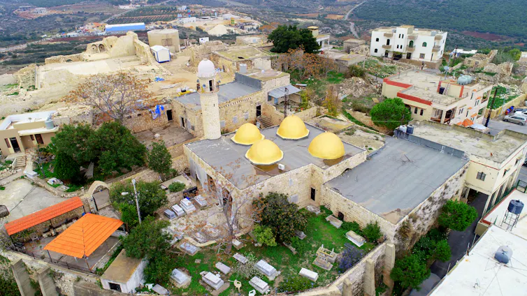 An aeriel photo of an old shrine with four domes and a minaret.