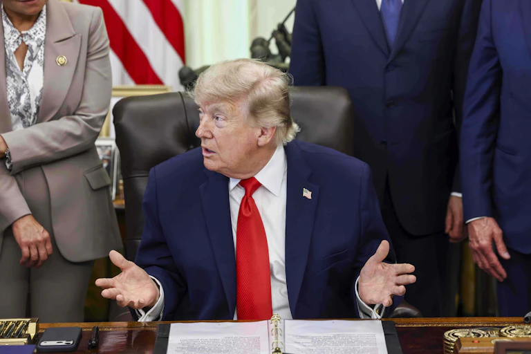 Donald Trump speaks to reporters during a signing ceremony in the Oval Office.