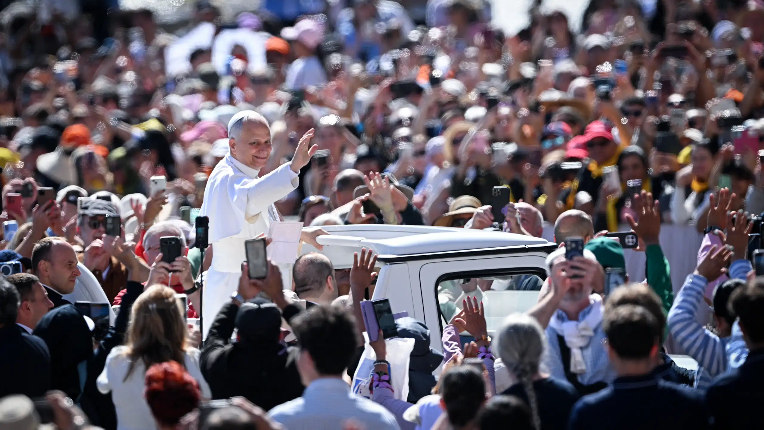 Le pape saluant la foule depuis sa papmobile.
