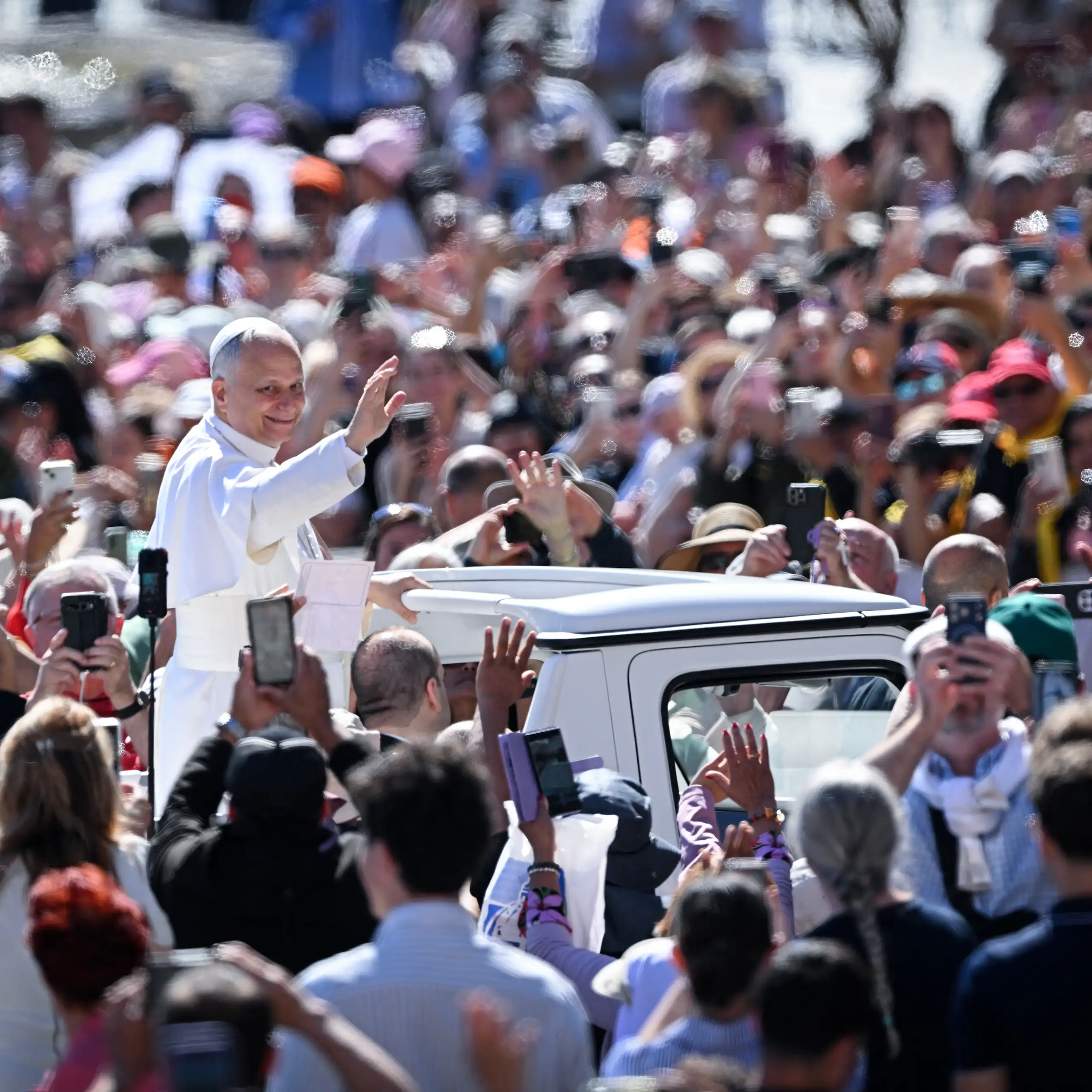 Le pape saluant la foule depuis sa papmobile.