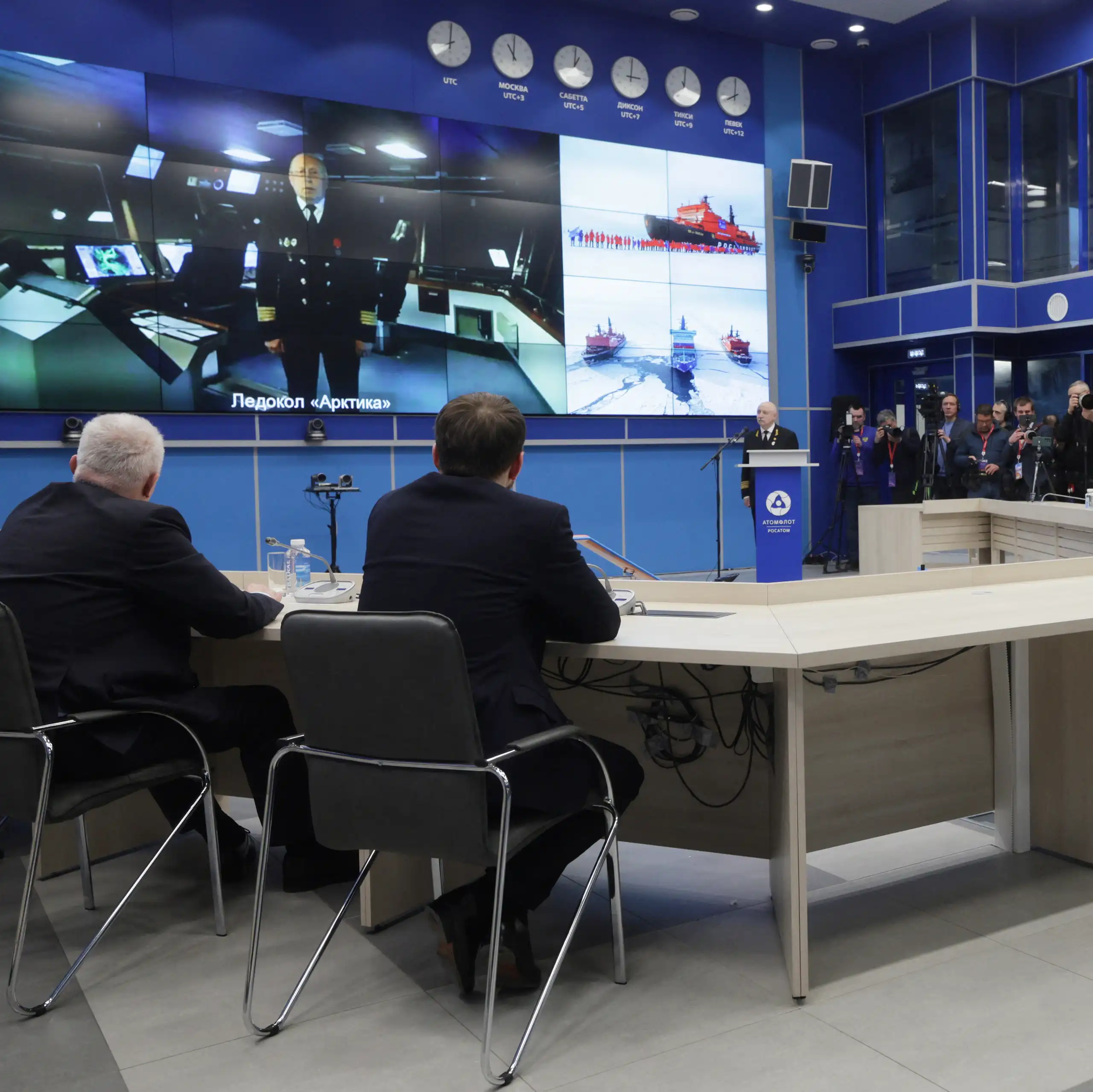 Vue sur la table de la réunion autour de laquelle des officiers et Vladimir Poutine échangent en visioconférence avec un officier.