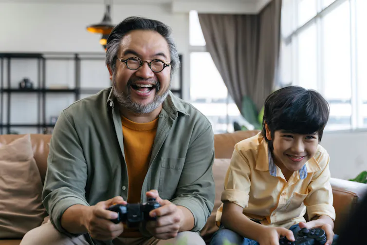 Un homme et un garçon souriant en jouant à un jeu vidéo