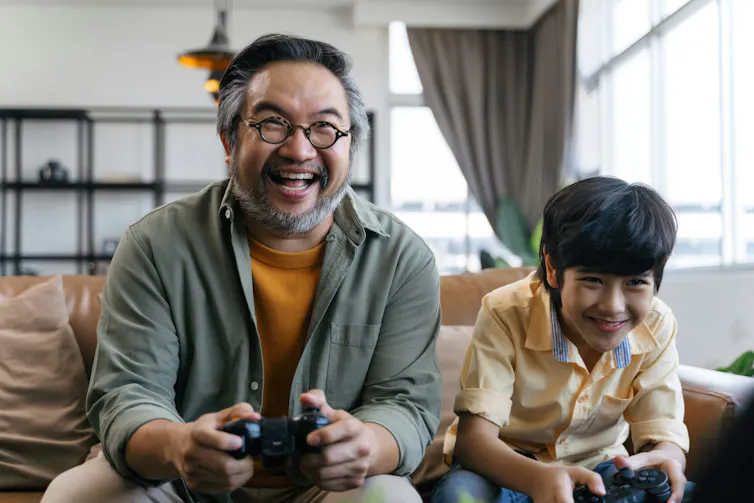 A man and a boy smiling while playing a video game