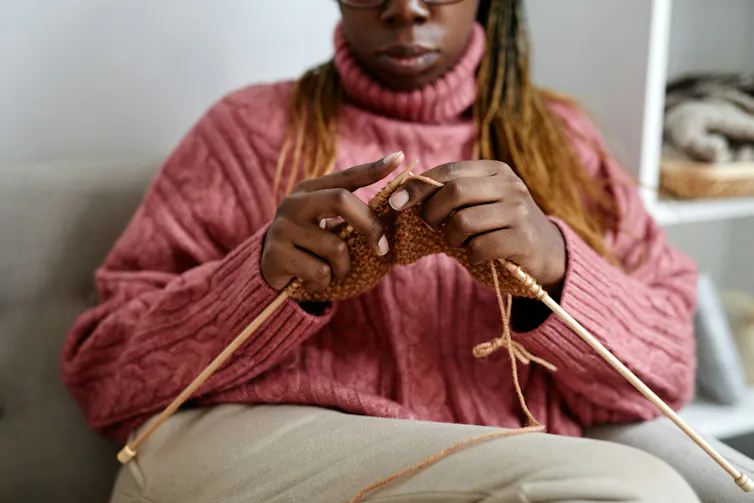 A woman in a pink sweater knitting