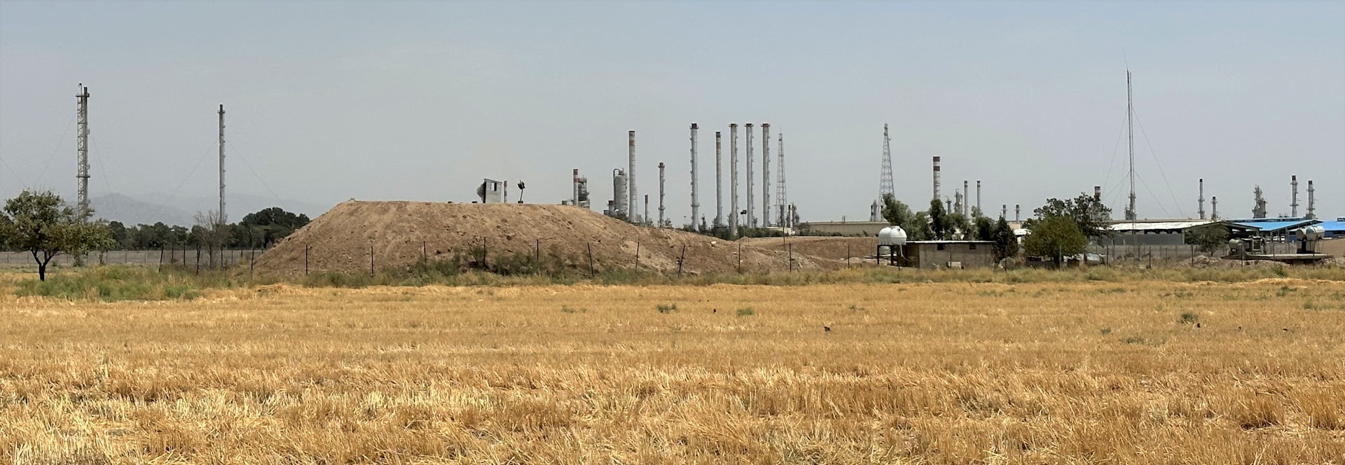 Campo amarillo y refinería de petróleo al fondo