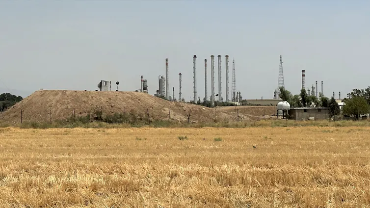 Vivir con riesgo industrial: cómo los complejos petroquímicos dan forma a la vida urbana 3 Campo amarillo y refinería de petróleo al fondo