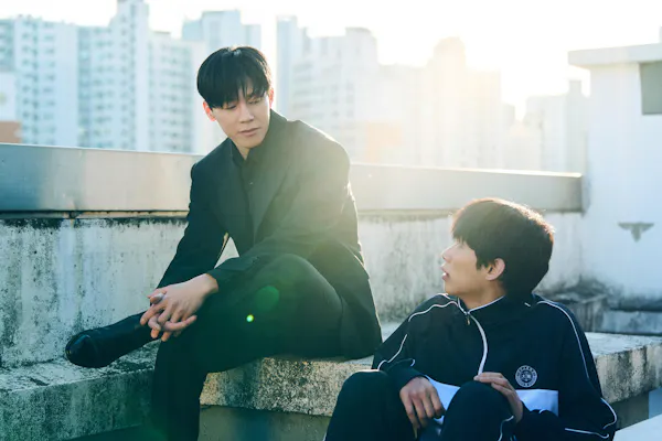 A man and a young male student have a conversation on a rooftop.