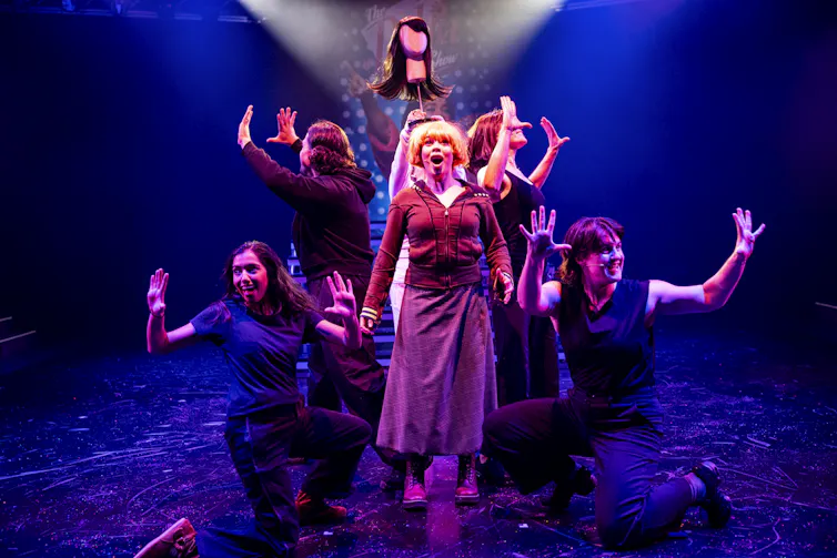 Members of a theatre cast perform a dance number onstage.