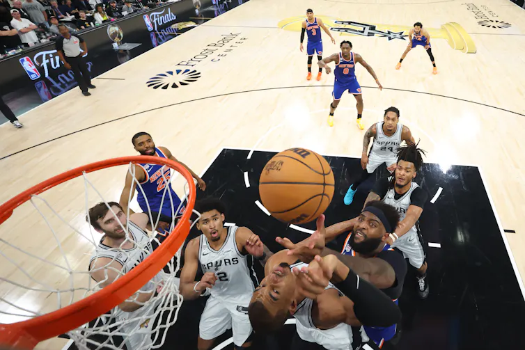Los hombres en la cancha de baloncesto saltan por la pelota.