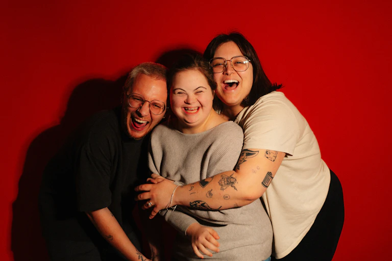 Three people hugging and laughing.