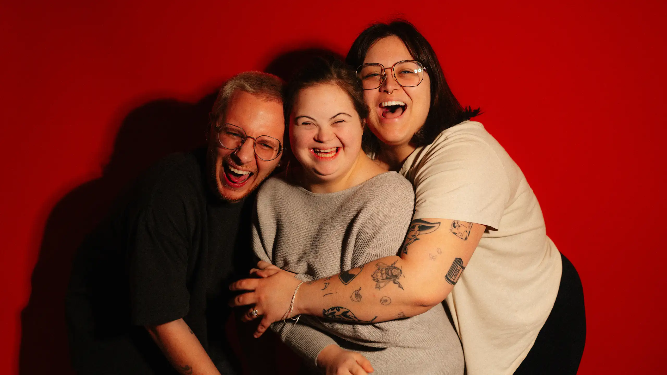 Three people hugging and laughing.