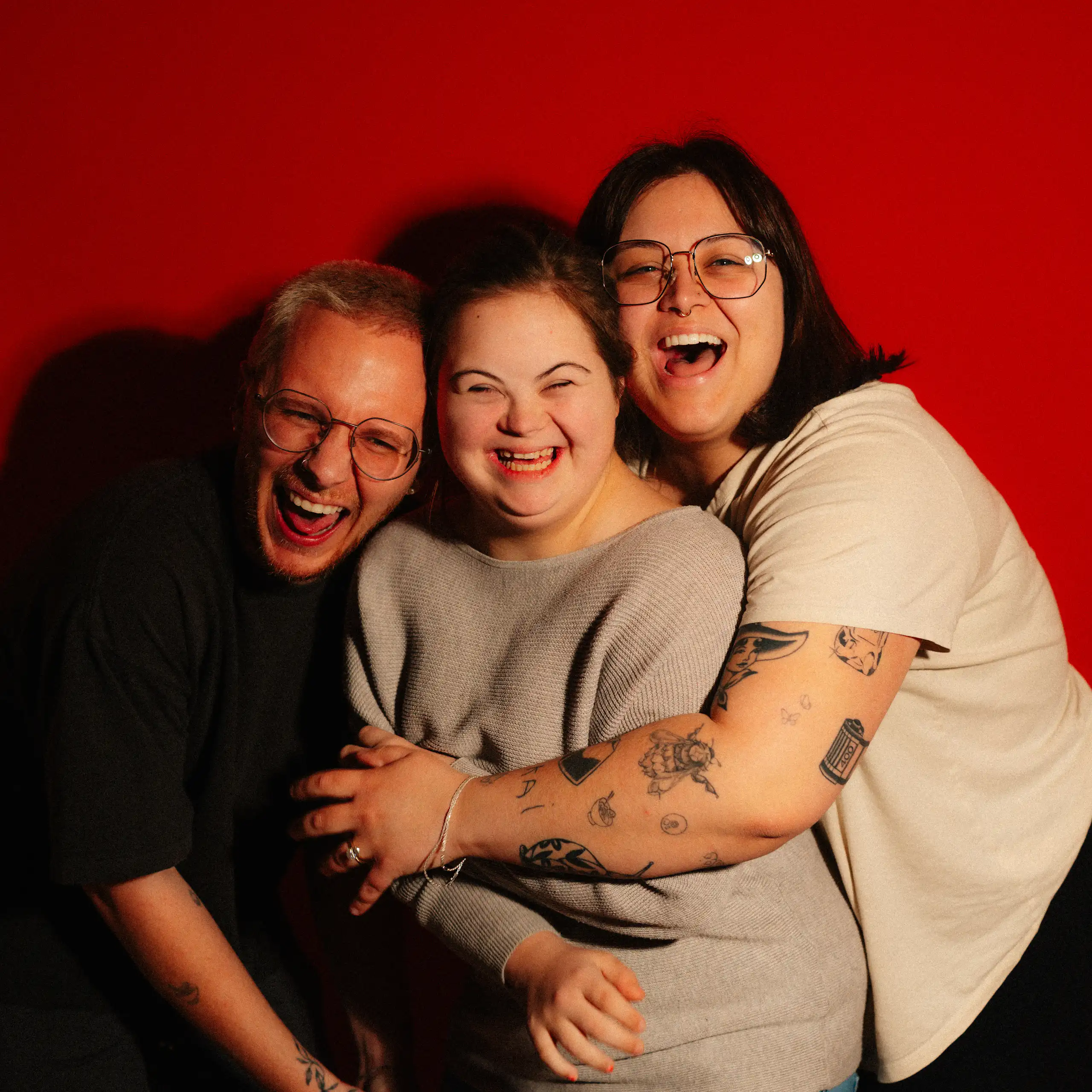 Three people hugging and laughing.