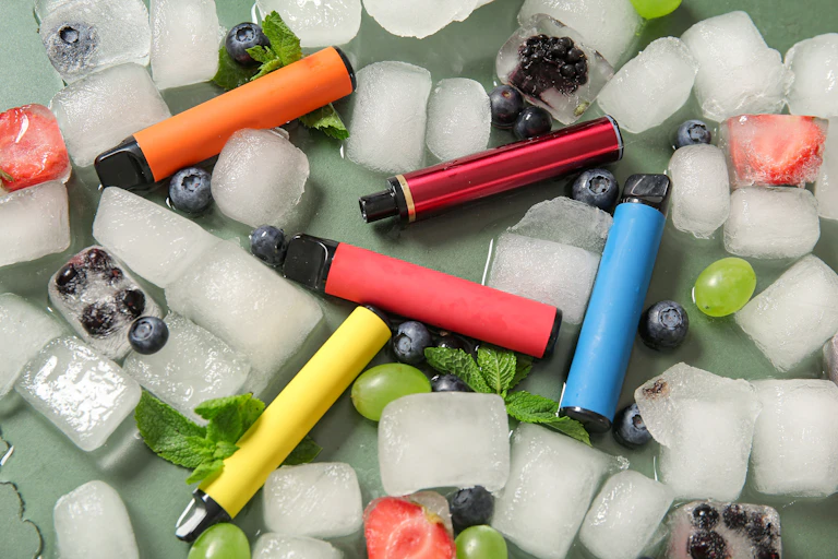 Vape pens on top of ice cubes and bits of fruit.
