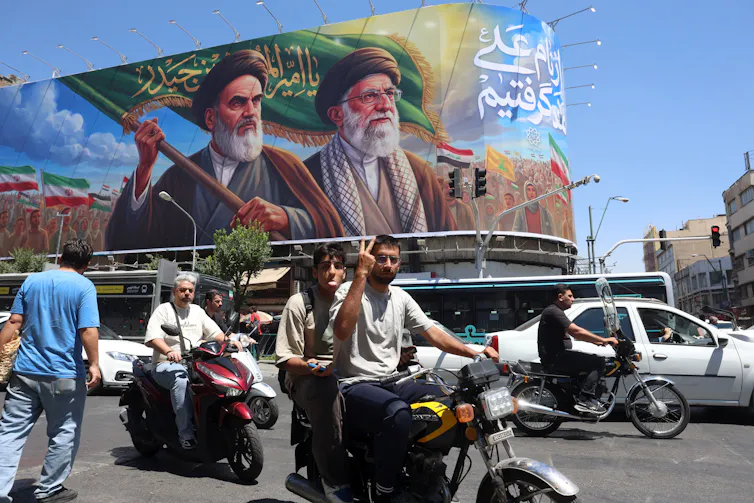Iranians ride motorcycles in Tehran past a poster of late Iranian supreme leaders Ayatollah Ruhollah Khomeini and Ayatollah Ali Khamenei .