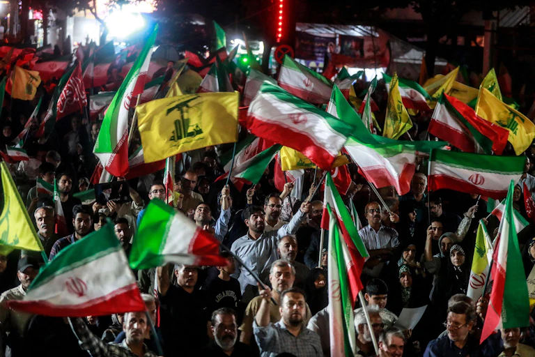 Pro-government supporters wave Iranian and Hezbollah flags during a state-organized rally in Iran.