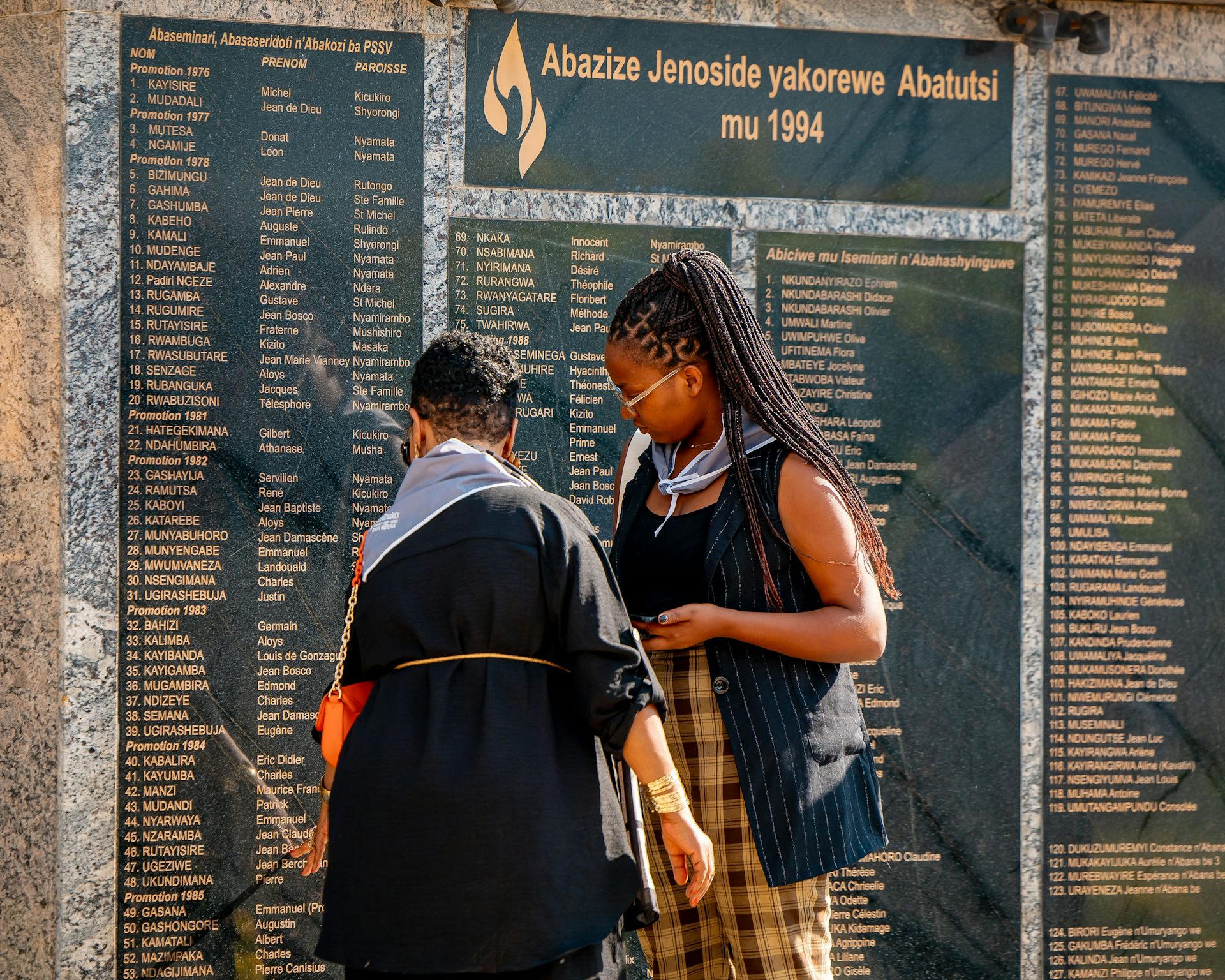 Deux femmes devant la stèle portant les noms des victimes du génocide.