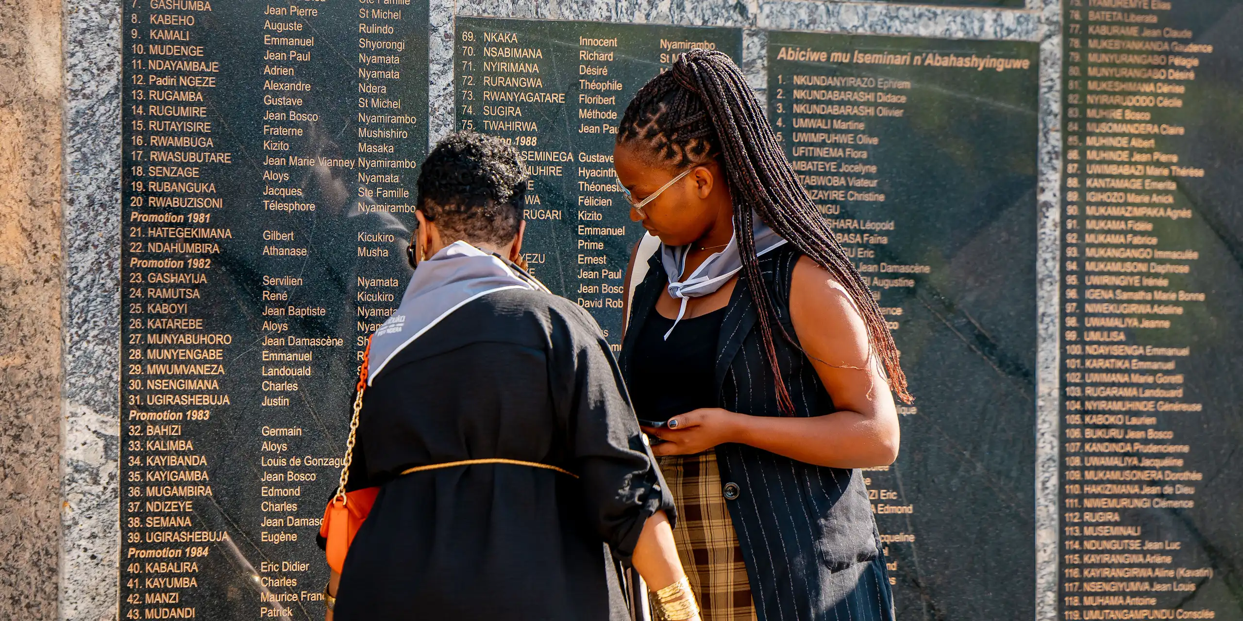 Deux femmes devant la stèle portant les noms des victimes du génocide.